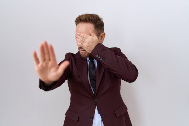 Middle age business man with beard wearing suit and tie covering eyes with hands and doing stop gesture with sad and fear expression. embarrassed and negative concept.  - Photo, Image