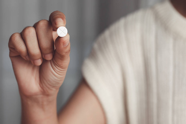 Рука азиатки держит белую таблетку для медицинских и медицинских концепций. - Фото, изображение