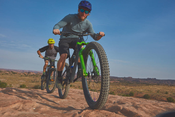 É tudo sobre a capacidade de suportar. Tiro de comprimento total de dois homens atléticos mountain bike através da natureza selvagem - Foto, Imagem