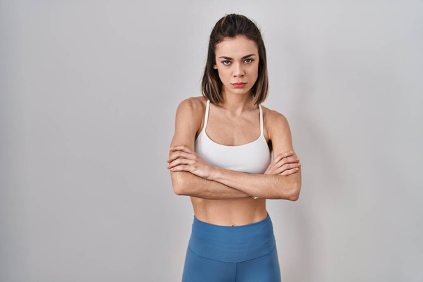 Hispanic woman wearing sportswear over isolated background skeptic and nervous, disapproving expression on face with crossed arms. negative person.  - Photo, Image