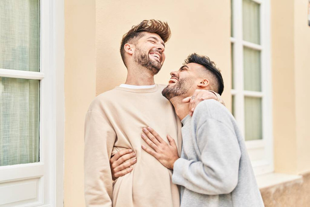 Jovem casal sorrindo confiante abraçando uns aos outros na rua - Foto, Imagem