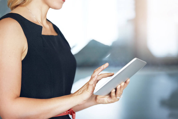 She works in a connected office. an unidentifiable businesswoman using a tablet in the office - Foto, imagen