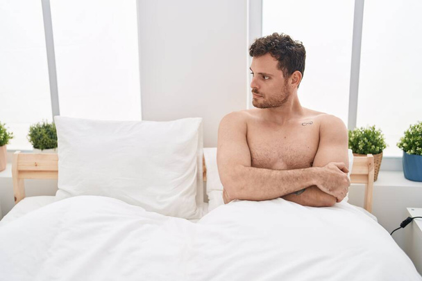 Young hispanic man unhappy sitting on bed at bedroom - Foto, Bild