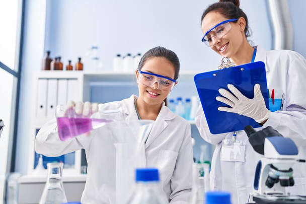 Woman and girl wearing scientist uniform working at laboratory - Foto, imagen