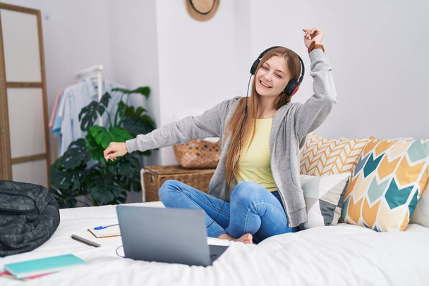 Young caucasian woman dancing and listening to music studying at bedroom - Photo, Image