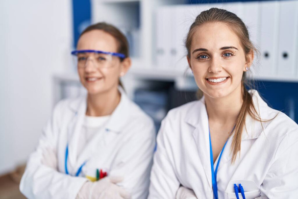 Dwie kobiety-naukowcy uśmiechające się pewnie z ramionami skrzyżowane gest w laboratorium - Zdjęcie, obraz