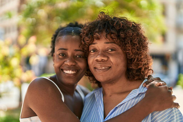 Αφρο-Αμερικανίδες μητέρα και κόρη αγκαλιάζονται στο πάρκο - Φωτογραφία, εικόνα