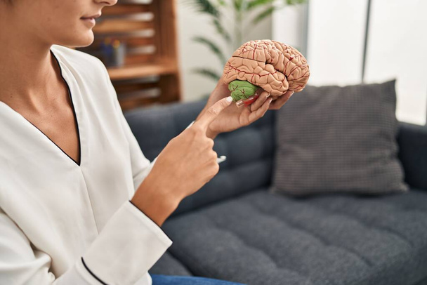 Mladá krásná hispánka psycholožka ukazující prstem na mozek na psychologické klinice - Fotografie, Obrázek