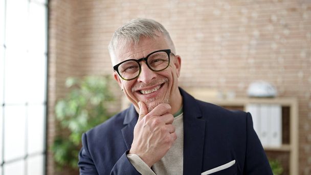 Grauhaariger Mann mittleren Alters lächelt selbstbewusst im Büro - Foto, Bild