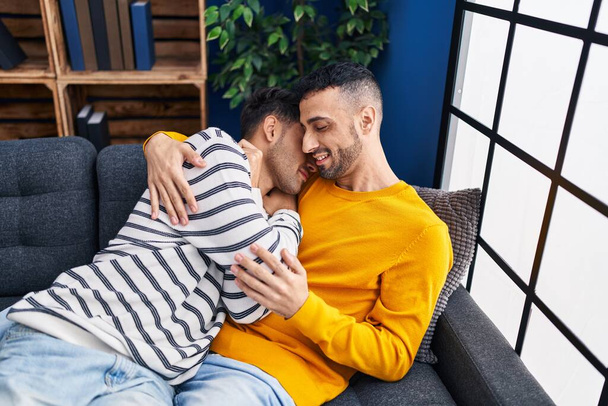 Two man couple hugging each other sitting on sofa at home - Fotografie, Obrázek