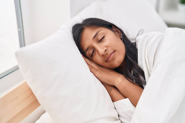 Young beautiful hispanic woman lying on bed sleeping at bedroom - 写真・画像