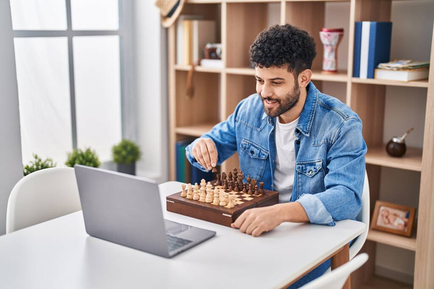 Nuori arabi mies ottaa online shakki peli istuu pöydällä kotona - Valokuva, kuva