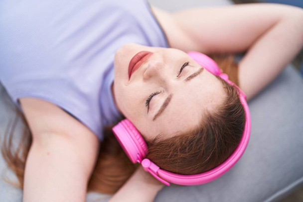 Молода руда жінка слухає музику, що лежить на дивані вдома
 - Фото, зображення