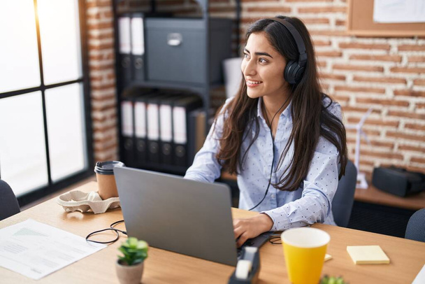Jovem hispânico menina trabalhador de negócios usando laptop e fones de ouvido trabalhando no escritório - Foto, Imagem