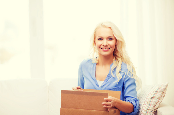 smiling young woman opening cardboard box - Foto, Bild