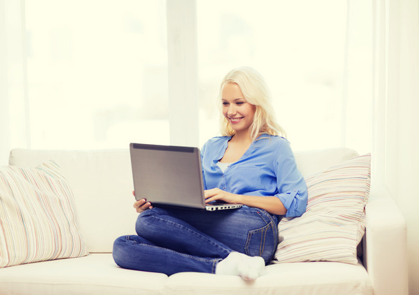 smiling woman with laptop computer at home - Fotó, kép