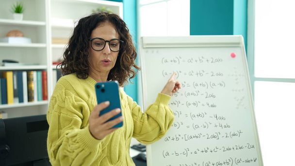 Μεσήλικας Ισπανίδα δασκάλα εξηγώντας online ασκήσεις μαθηματικών στο πανεπιστήμιο της βιβλιοθήκης - Φωτογραφία, εικόνα