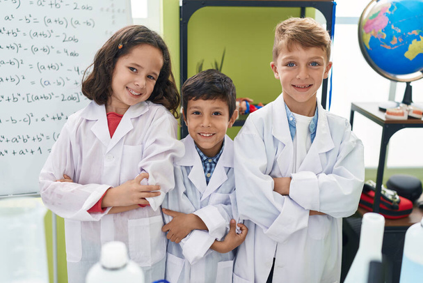 Grupa dzieci naukowcy studenci uśmiechający się pewnie stojąc z bronią przekroczył gest w klasie laboratoryjnej - Zdjęcie, obraz