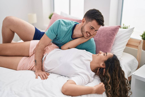 Young hispanic couple hugging each other lying on bed at bedroom - Фото, зображення