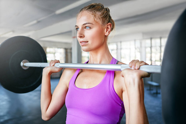 My quiet time involves heavy metal. a young woman working out with weights at the gym - Fotoğraf, Görsel