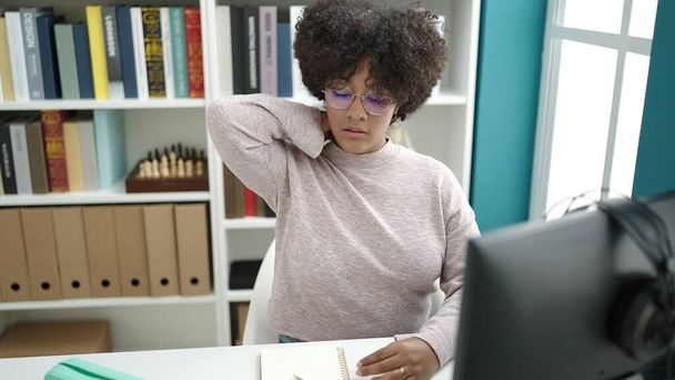 Young african american woman student using computer stressed at university classroom - Foto, Imagen