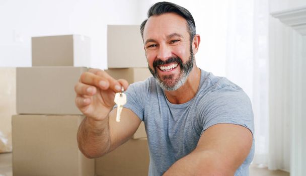 I made a great investment. a middle aged man holding the key to his new home - 写真・画像