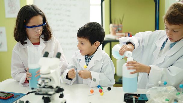 Gruppo di studenti bambini che versano liquido sulla bottiglia facendo esperimenti in classe di laboratorio - Foto, immagini