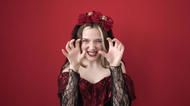 Joven mujer rubia con traje de katrina haciendo gesto de miedo sobre fondo rojo aislado - Foto, imagen