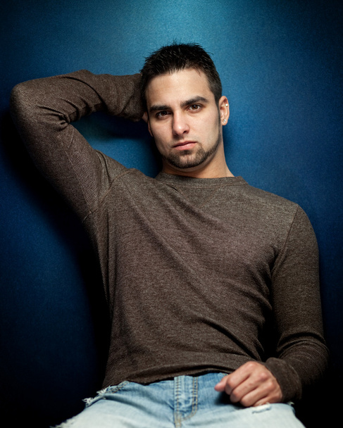 Moody portrait of a young man on a blue background. - Φωτογραφία, εικόνα