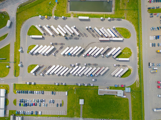 Вид с воздуха на товарный склад. Логистический центр в промышленной зоне города сверху. Вид с воздуха на погрузку грузовых автомобилей в логистическом центре - Фото, изображение