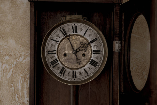 Old wooden clock with a pendulum hanging on the wall - Photo, Image