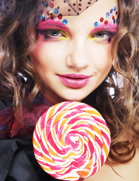 Meisje met creatieve make-up houdt lolly. - Foto, afbeelding