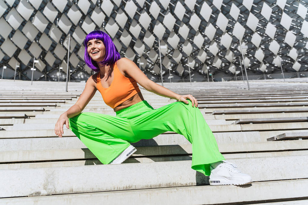 Carefree and happy woman wearing colorful sportswear on the street during summer day - 写真・画像