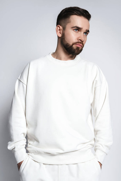 Handsome man wearing white sweatshirt against gray background - Zdjęcie, obraz