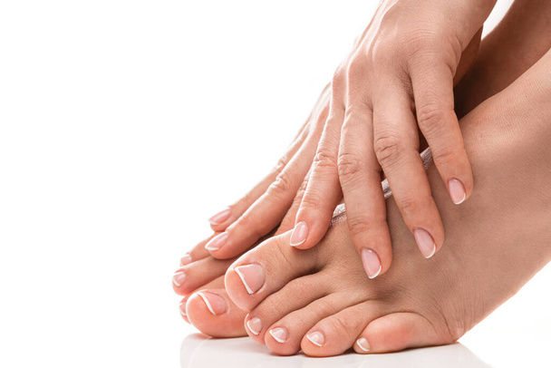 Closeup of female feet and hands with soft skin, french manicure and pedicure on white background - Φωτογραφία, εικόνα