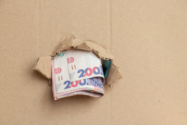 200 hryvnias sobresaliendo de un agujero en cartón, negocio - Foto, imagen