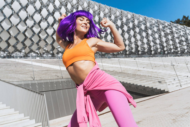 Carefree active woman dancer wearing colorful sportswear having fun on the street during sunny day - Foto, Imagen