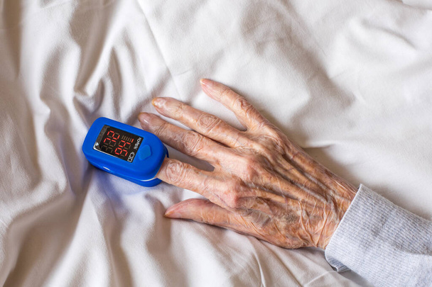 Close-up of an elderly womens hand with a pulse oximeter on her finger. High quality photo - Фото, изображение