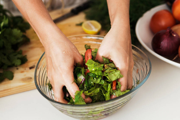 Closeup of female hands mixing vegetarian salad in the bowl - Фото, изображение
