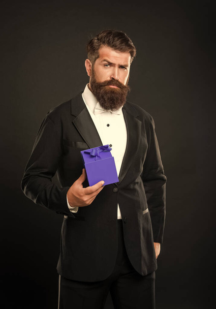 serious man in tuxedo bow tie formalwear on black background with box. valentines day. - Zdjęcie, obraz