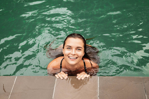 Portrait of cheerful smiling young woman relaxing in the swimming pool - Foto, immagini