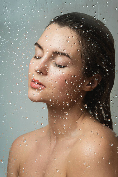 Portrait of beautiful and sensual woman captured through wet glass - Foto, Imagem