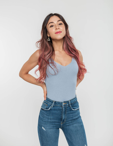 Красива модна молода дівчина з рожевим волоссям в стильному блакитному верху і джинси позує на білому тлі в студії
 - Фото, зображення
