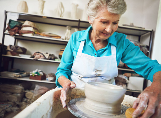 Kształtuje emeryturę, którą kocha. starsza kobieta robi ceramiczny garnek w warsztacie - Zdjęcie, obraz