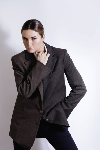 Fashionable studio portrait of young masculine woman against white background - Foto, Bild