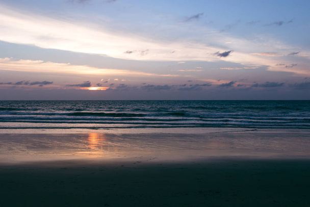 Piękny zachód słońca na plaży. Malownicze krajobrazy morskie z chmurami, falami i słońcem. - Zdjęcie, obraz