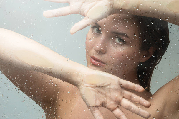 Portrait of beautiful and sensual woman captured through wet glass - Foto, imagen
