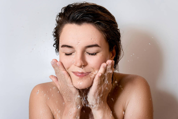 Portrait of young woman washing her face with clean water - Photo, image