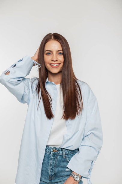 Šťastná krásná dívka modelka s roztomilým úsměvem v módní ležérní oblečení s košilí, tričko a džíny na bílém pozadí ve studiu - Fotografie, Obrázek