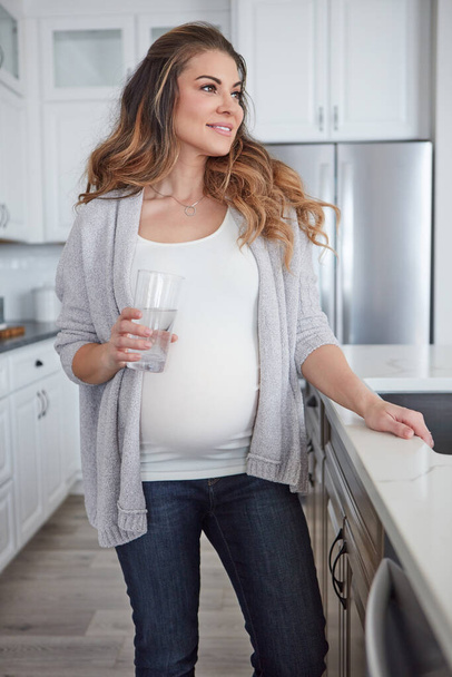 Nothing is more important than staying healthy throughout your pregnancy. 4k video footage of a pregnant woman drinking a glass of water at home - Photo, image